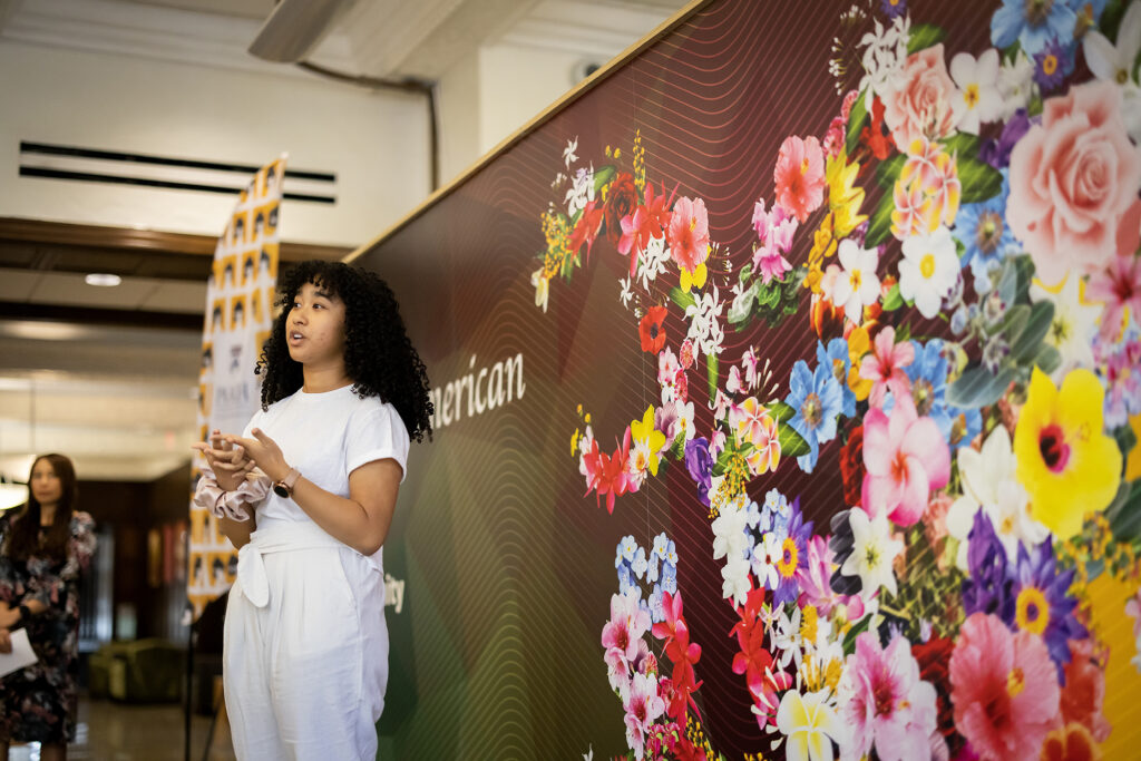 A student standing in front of the APA Mural at the ARCH.